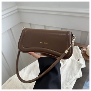 Close-up of dark brown leather underarm bag featuring gold logo and chain strap detail