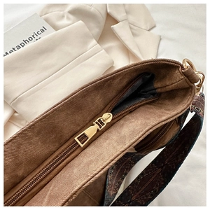 Close-up of golden zipper and ethnic print strap on a vintage dark brown bucket bag