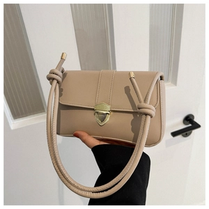 Detail of beige crossbody bag featuring golden shield lock and knotted shoulder strap