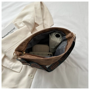 Close-up of brown bucket bag with wide patterned strap and spacious interior capacity