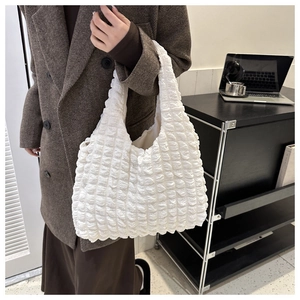 Close-up of white bubble texture cloud tote bag paired with an elegant wool coat