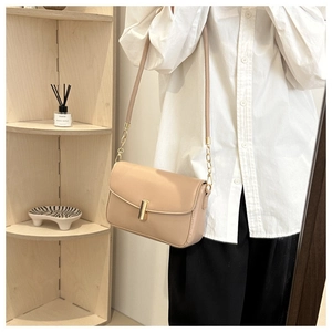 Detail of beige leather bag with a gold clasp and chain strap shown on a model