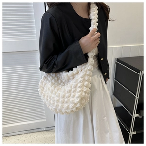 Close-up of a white shoulder bag with popcorn texture and crescent moon silhouette