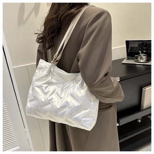 Détail d'un grand cabas matelassé blanc style doudoune porté à l'épaule par un mannequin