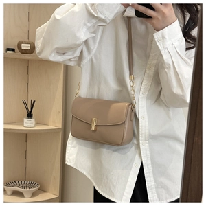 Close-up of a light brown leather shoulder bag with a gold buckle and shoulder strap