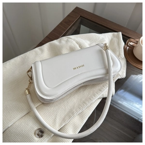 Close-up of minimalist cream crescent shoulder bag with gold logo and smooth leather texture