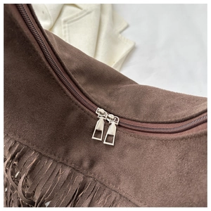 Detail of dark brown suede shoulder bag featuring long fringe and premium metal zippers