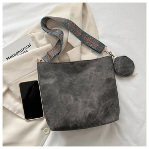 Detail of dark grey bucket bag with colorful woven strap and round coin purse