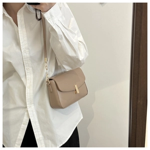 Detailed macro view of the gold bar clasp and smooth leather texture on the khaki crossbody bag