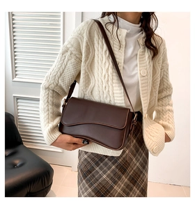 Detail of dark brown shoulder bag with a wavy flap design and high-quality leather texture