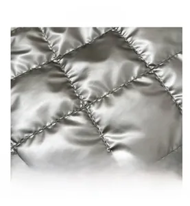 Gros plan sur un tissu argenté matelassé avec fini métallique brillant et couture nette