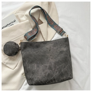 Flat lay of dark gray bucket bag with vintage texture and colorful jacquard strap