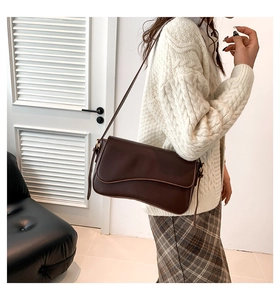 Side view of dark coffee faux leather shoulder bag with unique wavy flap and slim strap