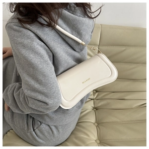 On-shoulder view of cream leather hobo bag with gold chain and XM BAGS logo detail