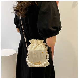 Detail of straw woven crossbody bag with daisy embroidery, pearl handle and chain strap