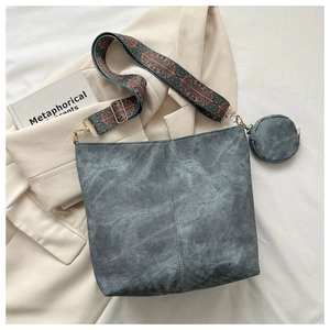 Detail of grey bucket bag with ethnic embroidered strap and small coin purse attachment