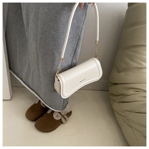 Close-up of white leather shoulder bag with gold hardware and XM & BAGS logo detail
