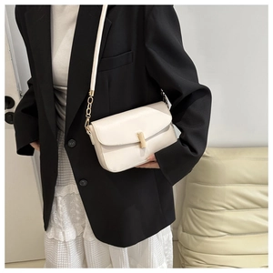 Detail of creamy white crossbody bag with gold rectangular buckle and chain strap