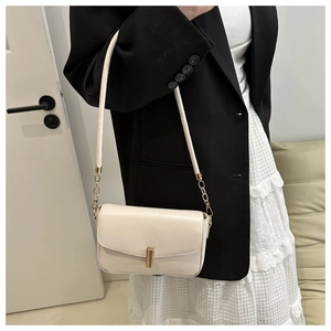 Detail of cream white leather shoulder bag with gold rectangular buckle and chain strap