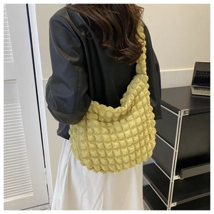 Detailed back view of a pale yellow pleated cloud shoulder bag worn by a female model
