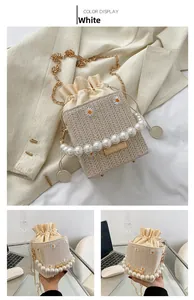Detail of straw woven bucket bag with daisy embroidery, pearl handle, and gold chain strap