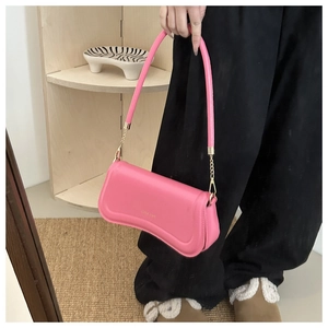 Detail of a pink leather baguette bag with golden chain strap and brand logo