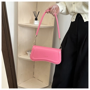 Detail of rose pink shoulder bag showing smooth faux leather texture and gold chain link