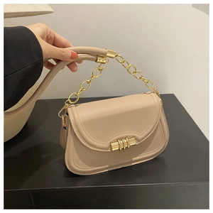 Dettaglio borsa a tracolla in pelle beige con catena dorata e chiusura a cilindro in metallo