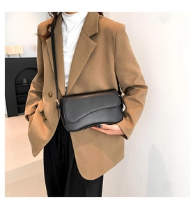 Chic black matte crossbody bag with curved flap and gold hardware on female model