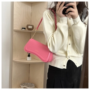 Pink shoulder bag detail showing golden chain strap and logo in a lifestyle mirror photo