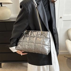 Détail du sac cabas matelassé argenté avec chaîne dorée porté par un mannequin