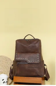 Close-up of vintage brown leather backpack with metal rivets and irregular flap design