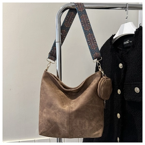 Detail of vintage brown bucket bag featuring a colorful bohemian style woven strap