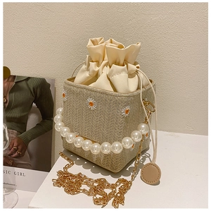 Close-up of straw bucket bag featuring daisy embroidery and pearl handle details