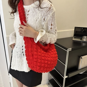 Detail of red bubble texture popcorn shoulder bag with wide strap on white blouse