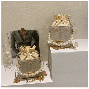Detail of straw bucket bag featuring daisy embroidery and elegant pearl handle