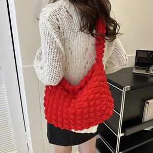 Detail of red popcorn textured cloud bag on model's shoulder with bright bubble fabric