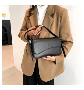 Detail of black flap shoulder bag with wave-edge design and gold metal hardware