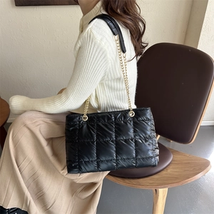 Détail du sac cabas matelassé noir avec bandoulière en chaîne dorée et patte d'épaule