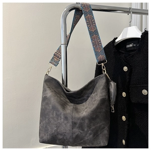 Close-up of retro gray bucket bag with vibrant bohemian embroidered shoulder strap