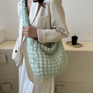 Detail of mint green pleated bubble shoulder bag texture on a model in white blazer