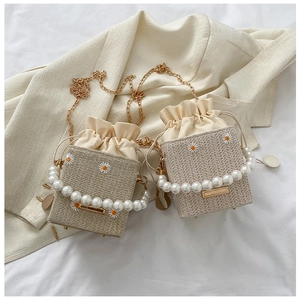 Detail of straw bucket bag with daisy embroidery, pearl handle and drawstring closure