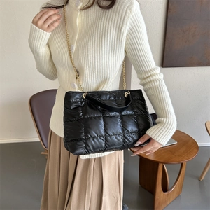 Sac fourre-tout matelassé noir avec chaîne dorée porté par un mannequin en intérieur