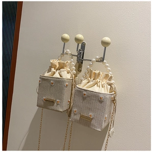 Detail view of woven straw bucket bag with daisy embroidery and pearl handle strap