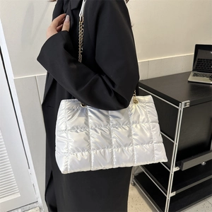 Détail d'un sac cabas argenté matelassé avec finition métallisée et chaîne dorée