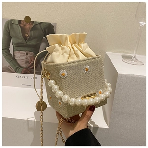 Detail of straw bucket bag with white daisy embroidery and large pearl handle grip