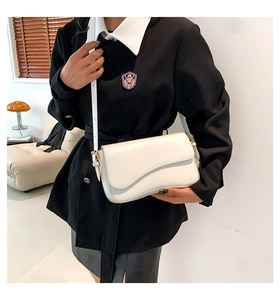Close-up of white shoulder bag featuring a unique irregular flap and adjustable strap