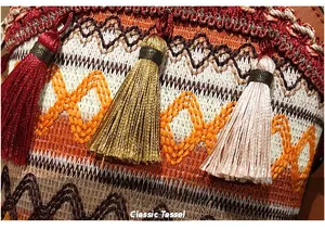 Macro detail of bohemian woven pattern and colorful hanging tassels on a bucket bag