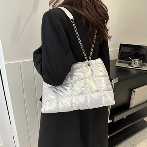 Détail du sac cabas matelassé argenté avec chaîne dorée sur un blazer noir