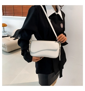 White leather shoulder bag with wavy flap edge styled on a black blazer jacket